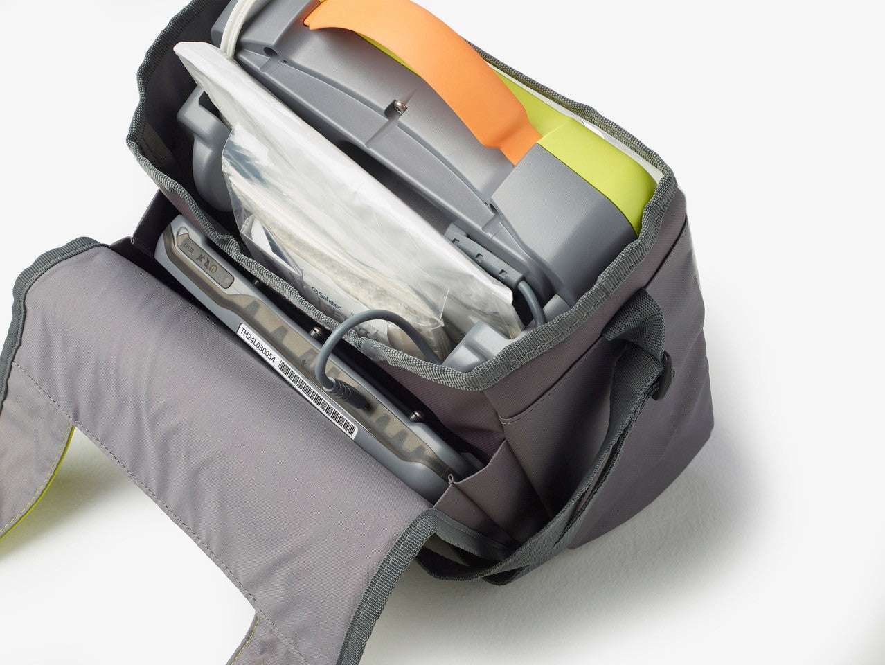 A grey medical device bag from The AED Shop, featuring AEDtrax and supplies including a ZOLL AED 3 for monitoring, is neatly organized inside and photographed from above.