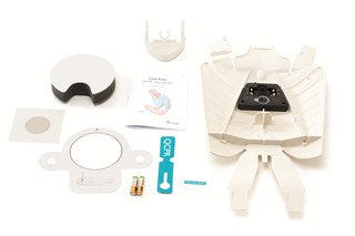 The Little Anne QCPR Upgrade Kit by Laerdal includes medical device components that are neatly arranged, featuring a white casing, an instruction booklet, batteries, and adhesive parts. It also comes with the innovative QCPR sensor compatible with the QCPR Training app for enhanced accuracy and functionality.