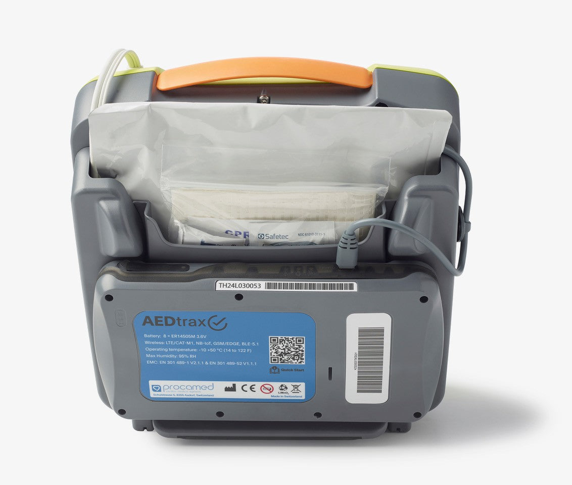 Back view of The AED Shop AEDtrax defibrillator displaying its battery pack, label, cables, and storage pouch—perfect for AED monitoring in any environment.