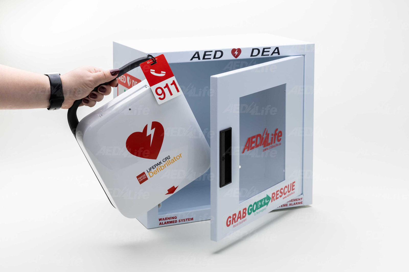 Hand removing a Physio-Control/STRYKER LIFEPAK CR2 Bilingual Complete Package defibrillator from an “AED Life” wall cabinet labeled “Grab, Go, Rescue.”.