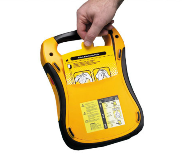 Yellow and black AED (Automated External Defibrillator) device held by a hand on a white background