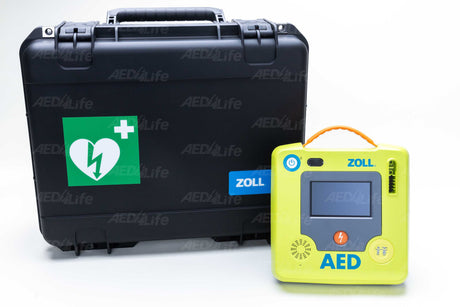 A ZOLL AED 3 device, known for its shock resistance, is placed next to the large ZOLL AED 3 Hard Case, which features a green heart and lightning symbol.