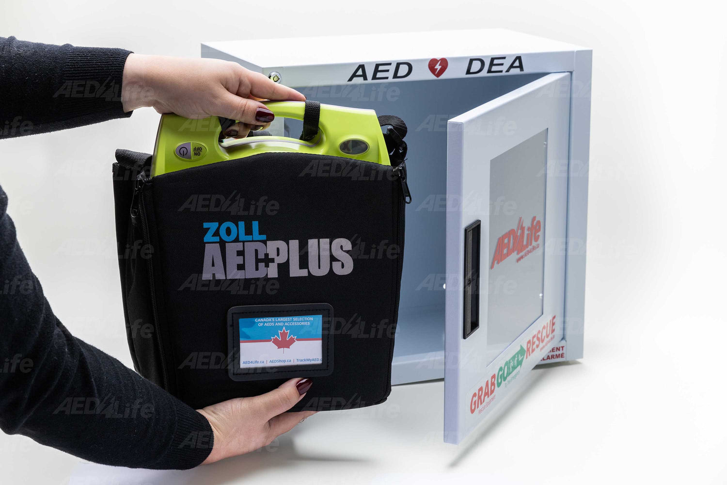 A person retrieves a ZOLL AED Plus - Complete Package, an automated external defibrillator with CPR feedback, from the wall-mounted cabinet.