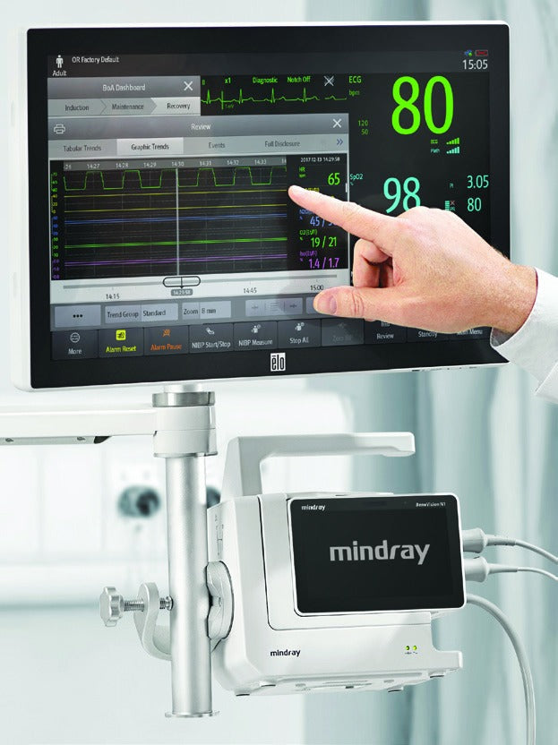 A hand touches a Mindray BeneVision N1 monitor displaying patient vitals.