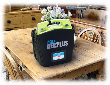 An AED Summer Cottage Rental from The AED Shop is placed on a wooden dining table in a cozy kitchen.