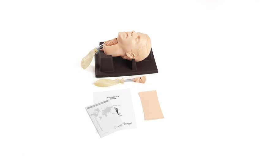 Laerdal's Cricoid Stick Trainer, an airway training mannequin with interchangeable tracheas and accessories, comes complete with a manual, pump, and pad, presented on a white background.