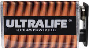 A close-up view of a rectangular Defibtech lithium battery 9V pack for the Lifeline AED, featuring an orange and black label.